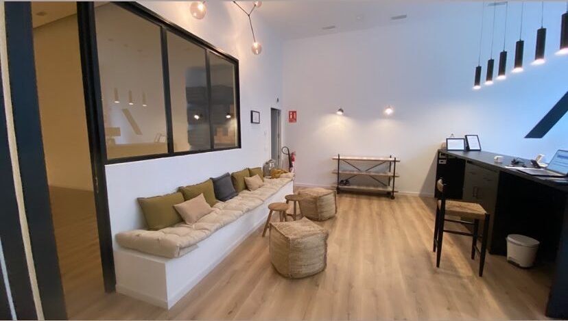 Salón amplio reformado con tarima, iluminación de techo y cerramiento interior tipo cristal.