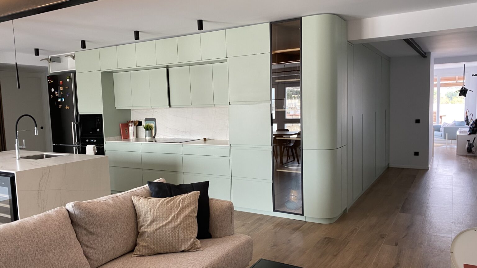 Espacio salón-cocina reformado con armarios a medida, acabados minimalistas y distribución abierta.
